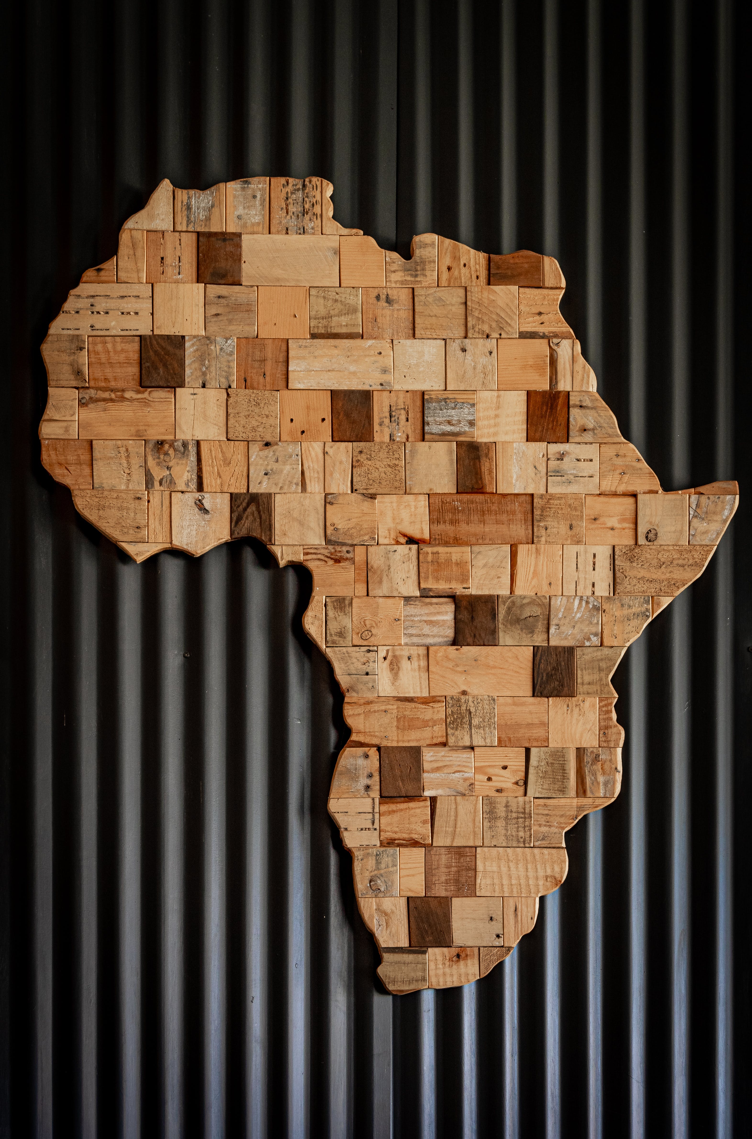 Image of a wooden map of Africa on a corrugated metal background